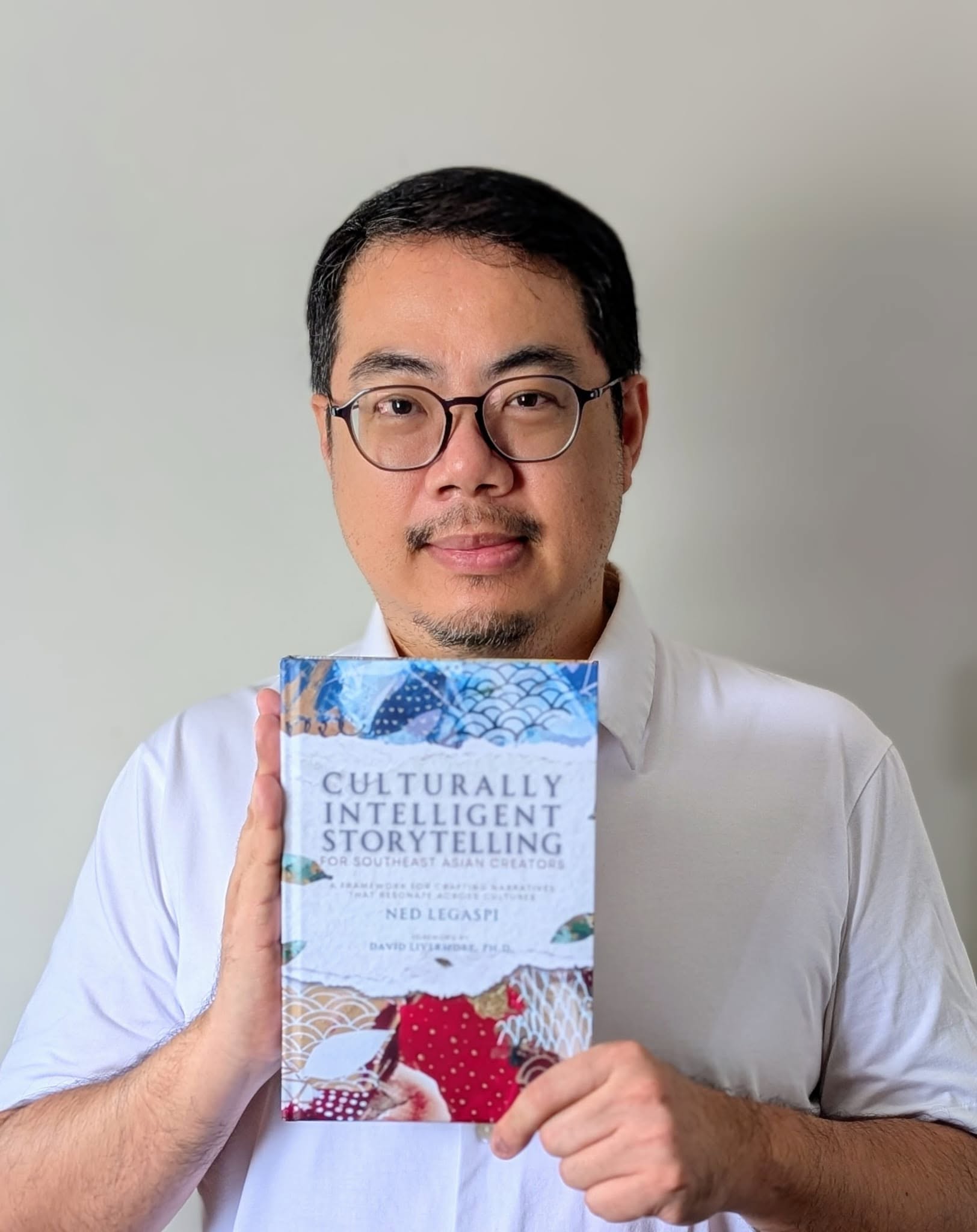 Singaporean poet-writer and MAI-Asia Board Chair Aaron Lee holding a copy of Culturally Intelligent Storytelling for Southeast Asian Creators