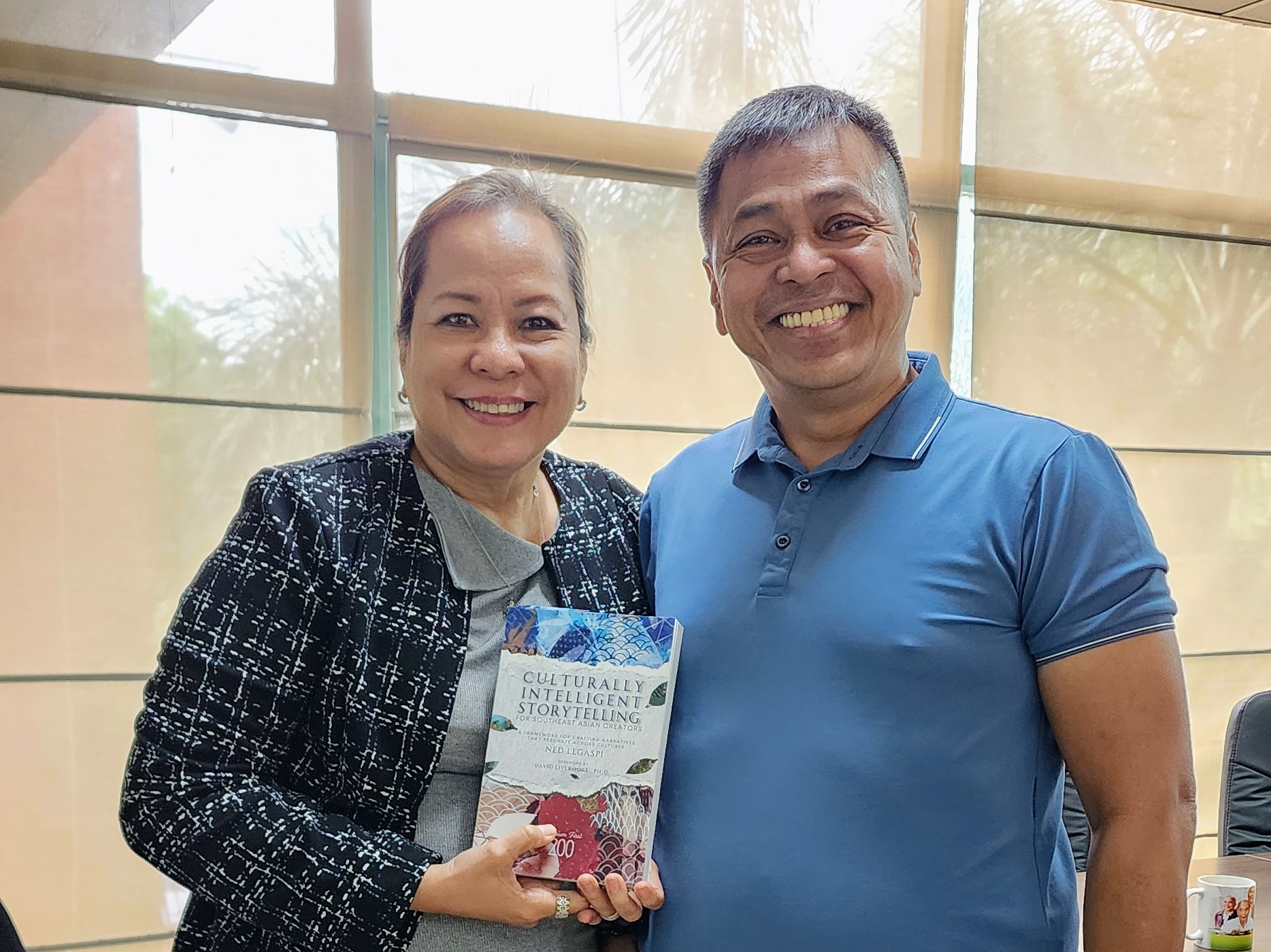 Jocelyn Balanag of the Commission on Higher Education with a copy of Culturally Intelligent Storytelling for Southeast Asian Creators