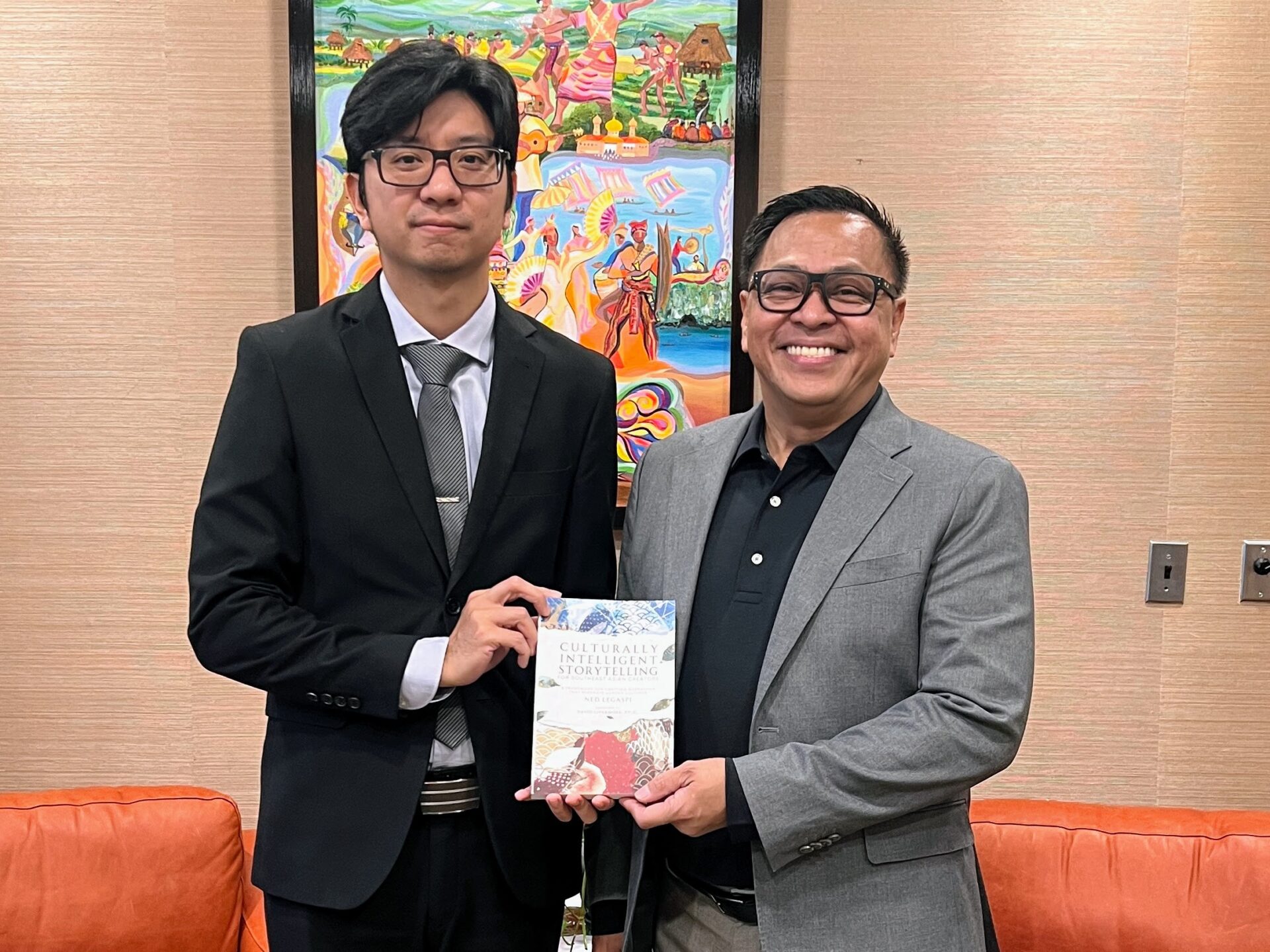 Ned Legaspi with Consul Mark Dominic E. Lim at the Philippine Embassy in Washington, D.C., holding a copy of Culturally Intelligent Storytelling for Southeast Asian Creators