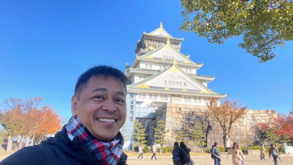 Ned Legaspi smiling in front of Osaka Castle during his terminal leave in December 2023