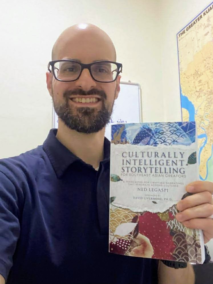 Zach Dorroh holding a copy of Culturally Intelligent Storytelling for Southeast Asian Creators in Kuala Lumpur, Malaysia